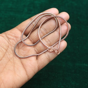 May include: A rose gold snake chain necklace with a lobster clasp closure.