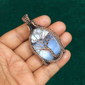 May include: A copper wire wrapped pendant featuring a white and gray dendritic agate stone with a tree design.