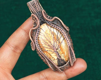 May include: A copper wire wrapped pendant featuring a tree of life design with a light brown and white agate stone.
