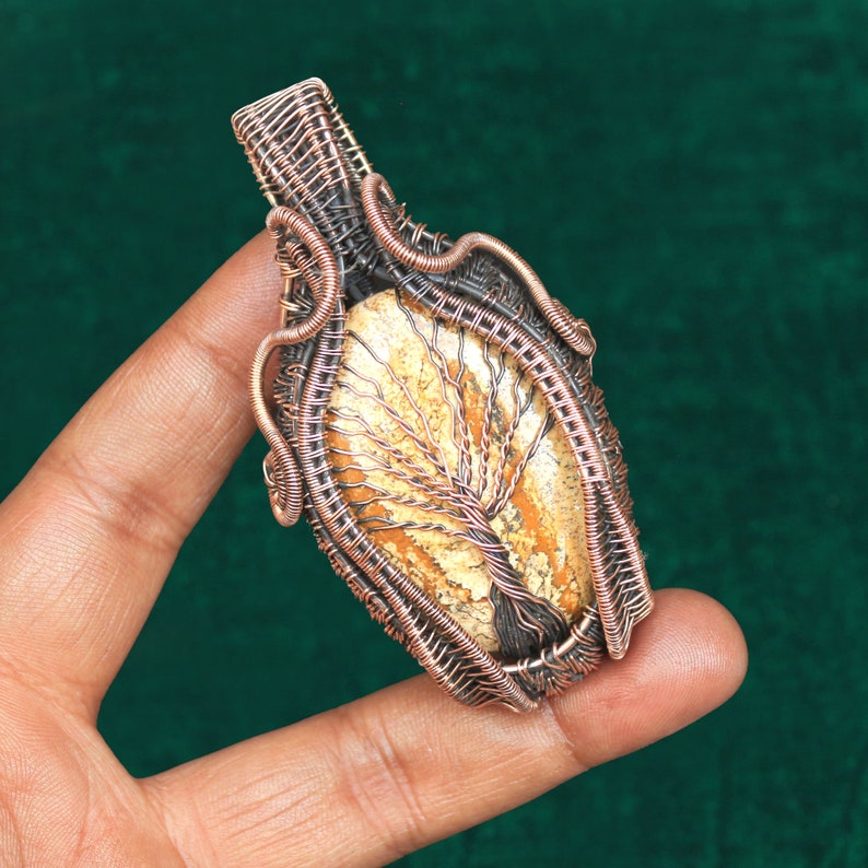 May include: A copper wire wrapped pendant featuring a tree of life design with a light brown and white agate stone.
