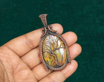 May include: A copper wire wrapped pendant featuring a tree of life design with a yellow, brown, and green agate stone.