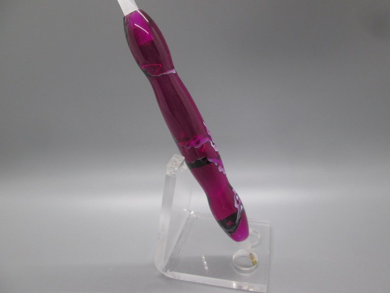 May include: A purple and white swirl pen with a black accent, displayed on a clear acrylic stand.