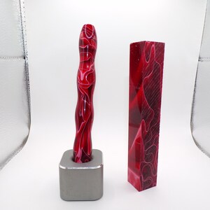 May include: Two red and white resin blanks for crafting. One blank is a straight block, the other is a curved, twisted shape.