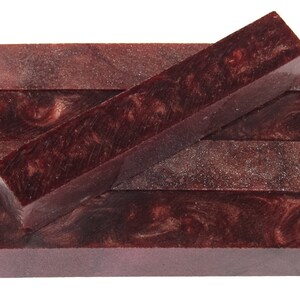 May include: Four burgundy and silver pen blanks with a swirling pattern. The blanks are stacked on top of each other.