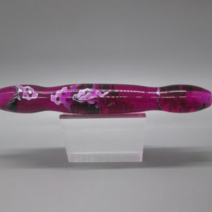 May include: A pink and black marbled pen with a clear tip and a gold metal tip.