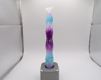 May include: A purple and blue glass pipe with a swirl design. The pipe is sitting on a gray stand.