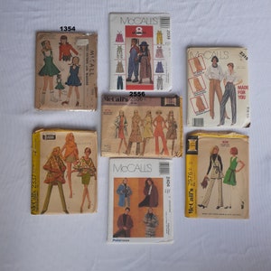 Puede incluir: Una colección de patrones de costura vintage para ropa. Los patrones están impresos en papel y presentan ilustraciones de las prendas. Los patrones incluyen McCall's 2556, McCall's 2337, McCall's 2576, McCall's 2404, McCall's 2039 y McCall's 2315.