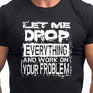 May include: Black crew neck t-shirt with white text: "LET ME DROP EVERYTHING AND WORK ON YOUR PROBLEM." The shirt is worn by a person with short brown hair.