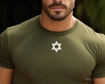 May include: A man wearing a green short-sleeved t-shirt with a white six-pointed star on the front. He is standing in front of a blurred background.