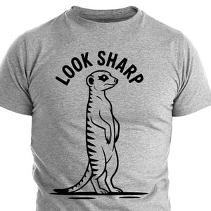Puede incluir: Camiseta gris jaspeado con una ilustración negra de un suricato de pie. El texto "LOOK SHARP" está arqueado sobre el suricato. La camiseta está hecha de un material suave.