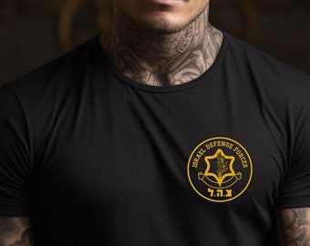 May include: Black crew neck t-shirt with a gold and yellow emblem that reads "Israel Defense Forces" and the Hebrew letters "צה״ל". The shirt is short-sleeved and has a classic fit.