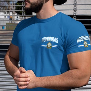 May include: A royal blue t-shirt with white text that reads "HONDURAS" and a white stripe with the Honduran flag in the center.