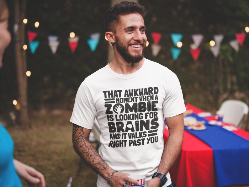 May include: White t-shirt with black text that reads "That awkward moment when a zombie is looking for brains and it walks right past you".