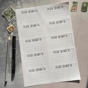 May include: A white sheet of paper with the text "PLEASE DELIVER TO" repeated multiple times in a handwritten font. The paper is folded in half and has a lined pattern.