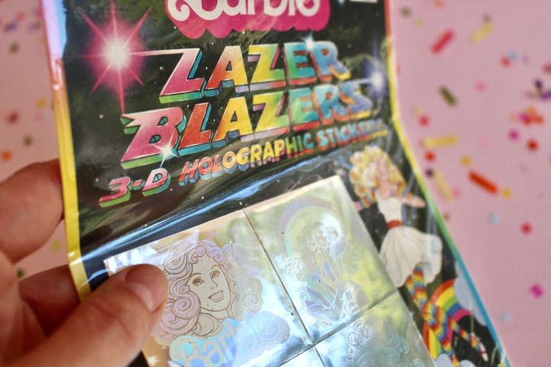 Puede incluir: Un paquete de pegatinas hologr&aacute;ficas 3D Lazer Blazers con un dise&ntilde;o de arco&iacute;ris. Las pegatinas son hologr&aacute;ficas y tienen un efecto arco&iacute;ris.