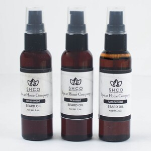 May include: Three brown glass bottles with black pump tops and white labels. The labels read "SHCO Spa at Home Company" and list "Unscented Beard Oil" and "Scented Beard Oil" with a net weight of 2 ounces.