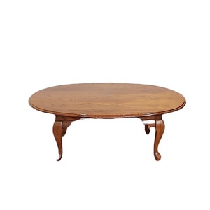 May include: A wooden oval coffee table with a brown finish and four cabriole legs.