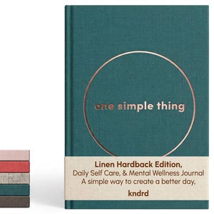 May include: A teal linen hardback journal with a copper-coloured circle and the text one simple thing on the cover. A beige paper band features the text Linen Hardback Edition, Daily Self Care, & Mental Wellness Journal A simple way to create a better day, kndrd. A stack of five journals in various colours sits to the left.