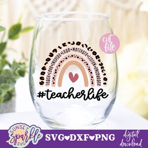 May include: A pink and brown rainbow with the words "Teach-Love-Inspire-Lead-Motivate-Listen-Encourage" around it. The rainbow has a small pink heart in the center. Below the rainbow is the text "#teacherlife".
