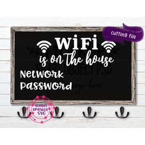 May include: A black chalkboard with white text that reads "WiFi is on the house Network Password" with two wifi symbols and a space for the password. The chalkboard is framed in wood and hanging on a white wall.