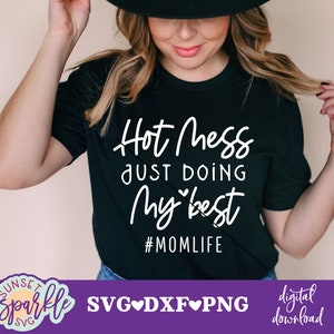 Puede incluir: Camiseta negra con el texto blanco "Hot mess just doing my best #momlife". La imagen también incluye el texto "SVG DXF PNG" y "descarga digital". La camiseta la lleva una persona.