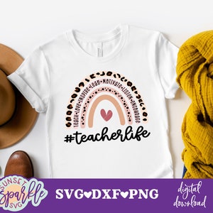 May include: A white t-shirt with a rainbow design and the text "#teacherlife". The rainbow is made of pink, peach, and white stripes with black polka dots. The text "Teach-Love-Inspire-Lead-Motivate-Listen-Encourage" is written around the rainbow.