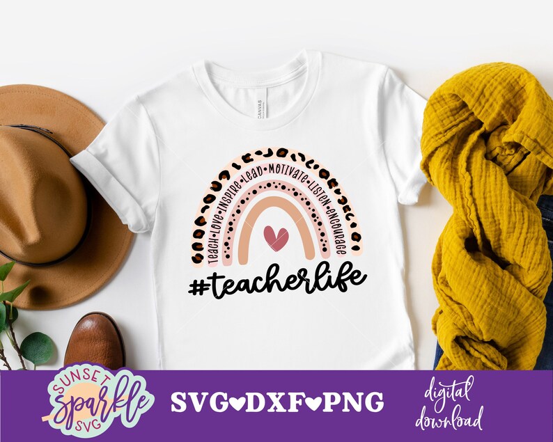 May include: A white t-shirt with a rainbow design and the text "#teacherlife". The rainbow is made of pink, peach, and white stripes with black polka dots. The text "Teach-Love-Inspire-Lead-Motivate-Listen-Encourage" is written around the rainbow.