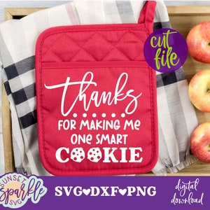 May include: Red quilted pot holder with the text "thanks......for making me one smart cookie" in white. The pot holder is on a checkered fabric with apples in the background.