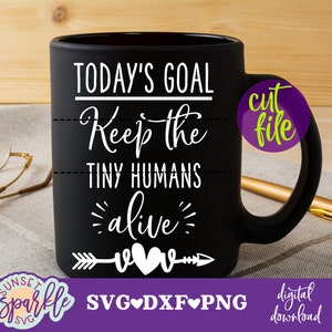 May include: Black coffee mug with white text that reads "TODAY'S GOAL Keep the TINY HUMANS alive" with a white arrow and two hearts. The mug is on a brown and white striped surface.
