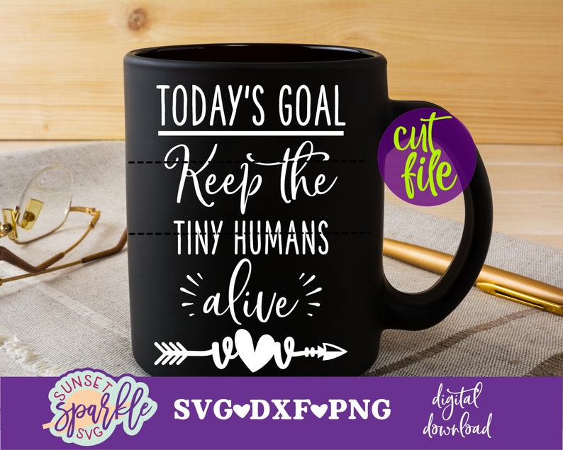 May include: Black coffee mug with white text that reads "TODAY'S GOAL Keep the TINY HUMANS alive" with a white arrow and two hearts. The mug is on a brown and white striped surface.