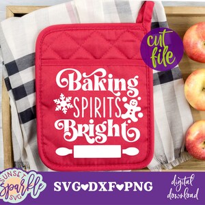 May include: Red quilted pot holder with the text "Baking Spirits Bright" in white, a snowflake, and a gingerbread man. The pot holder is on a checkered fabric background.