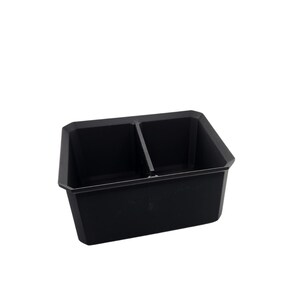 May include: A black plastic tray with two compartments. The tray is designed to hold small items, such as tools or craft supplies.
