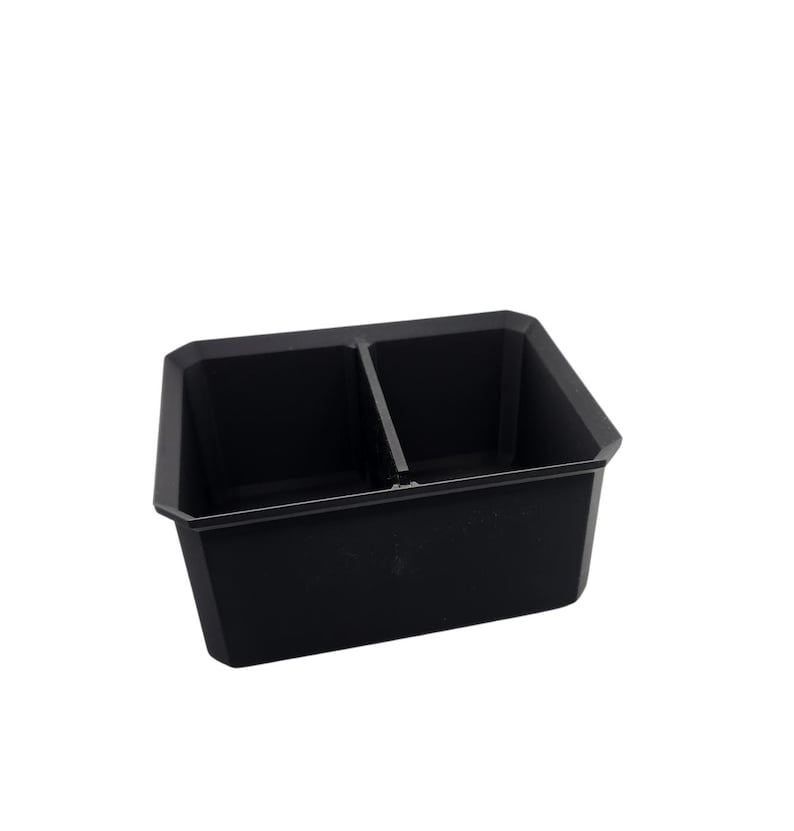 May include: A black plastic tray with two compartments. The tray is designed to hold small items, such as tools or craft supplies.