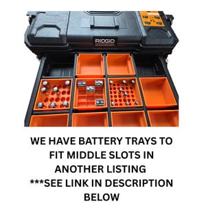 May include: Black RIDGID Pro Gear System tool box with orange battery trays. The trays are filled with various batteries. The text on the image reads: "WE HAVE BATTERY TRAYS TO FIT MIDDLE SLOTS IN ANOTHER LISTING ***SEE LINK IN DESCRIPTION BELOW."