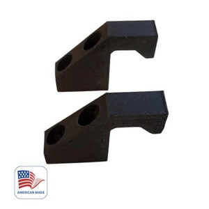 May include: Two black plastic brackets with two holes each. The brackets are angled and have a curved handle.