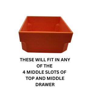 May include: An orange plastic storage bin with a rectangular shape. The bin has a slightly flared top and a stepped base. Text on the image reads: "THESE WILL FIT IN ANY OF THE 4 MIDDLE SLOTS OF TOP AND MIDDLE DRAWER."