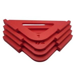 May include: A stack of red plastic tile leveling spacers. Each spacer is a right-angle shape with a raised edge and a central opening. The spacers are labeled with the numbers 1 and 1/2.