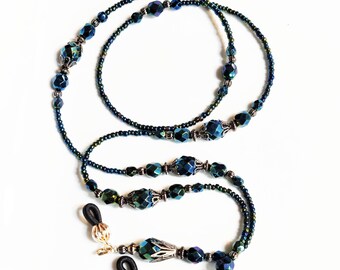 May include: A dark blue and green beaded eyeglass chain with silver accents. The chain has two loops at the ends for attaching to glasses.