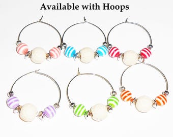 May include: Six wine glass charms with silver hoops and colorful striped beads. Each charm has a white bead in the center.