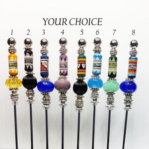 May include: A collection of eight decorative skewers with various colorful bead designs. Each skewer features a silver-toned metal top and base, with unique patterns and colors on the beads, including yellow, black, blue, purple, green, and orange.