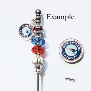 May include: A decorative silver pin with a New England Patriots logo charm. The pin has red, blue, and silver beads. The text "Example" is visible. A separate Patriots logo charm and a small silver pin are also shown.