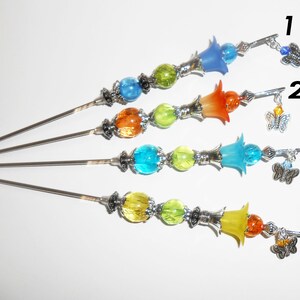 May include: Four decorative hair sticks with colorful glass beads and flower-shaped accents. Each stick features a different color scheme: blue, orange, turquoise, and yellow. Small butterfly charms dangle from the top of each stick, adding a whimsical touch.