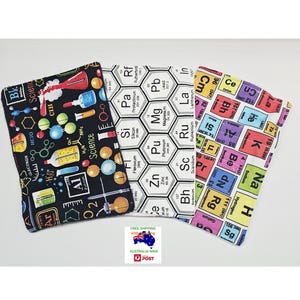 May include: Three fabric items with science-themed patterns. One has a black background with science tools and text. Another shows a periodic table of elements in white and black. The third has a colourful periodic table design.