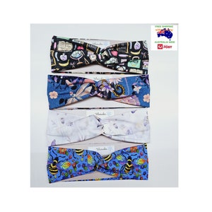 May include: Four different patterned headbands. The top headband is black with a school theme, the second is blue with a floral pattern, the third is white with a floral pattern, and the bottom is blue with a bee pattern.