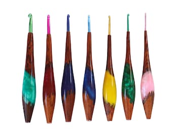 Può includere: Set di sette uncinetti colorati con manici in legno e dettagli in resina. Gli uncinetti sono di diversi colori, tra cui verde, rosa, blu e giallo.