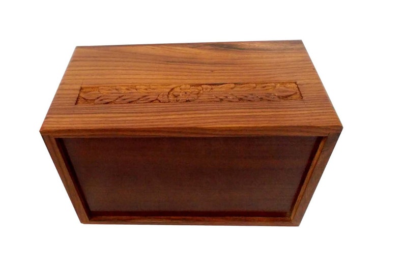 May include: A wooden box with a carved design on the top. The box is made of dark wood and has a natural finish.