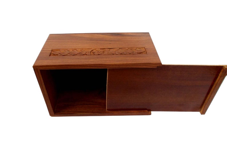 May include: A wooden box with a hinged lid. The box is made of dark brown wood and has a carved design on the top. The lid is open and the inside of the box is empty.