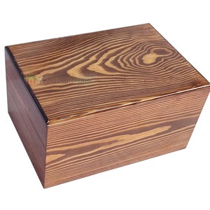 May include: A rectangular wooden box with a natural wood grain finish. The box has a dark brown trim around the edges. The box is made of pine wood.