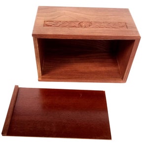May include: A wooden box with a carved design on the lid and a separate lid. The box is made of dark wood and has a natural finish.