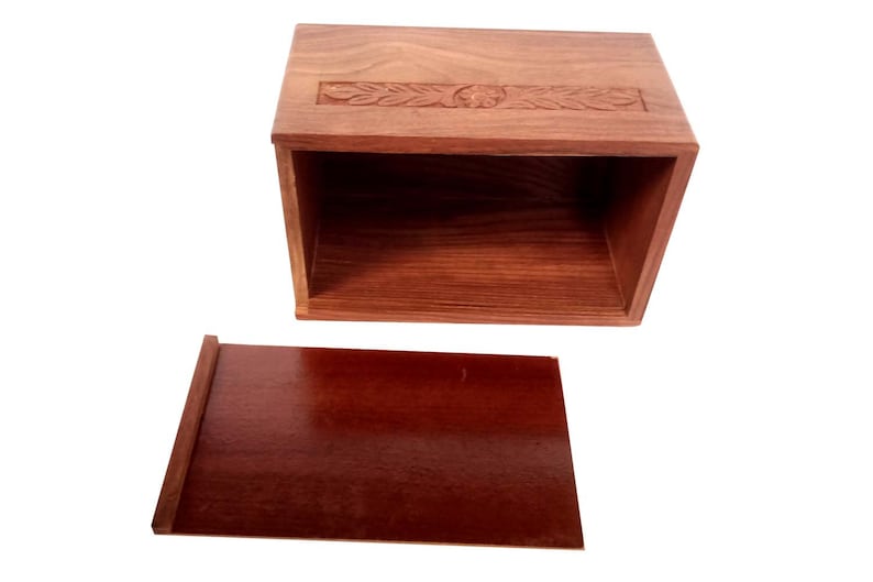 May include: A wooden box with a carved design on the lid and a separate lid. The box is made of dark wood and has a natural finish.